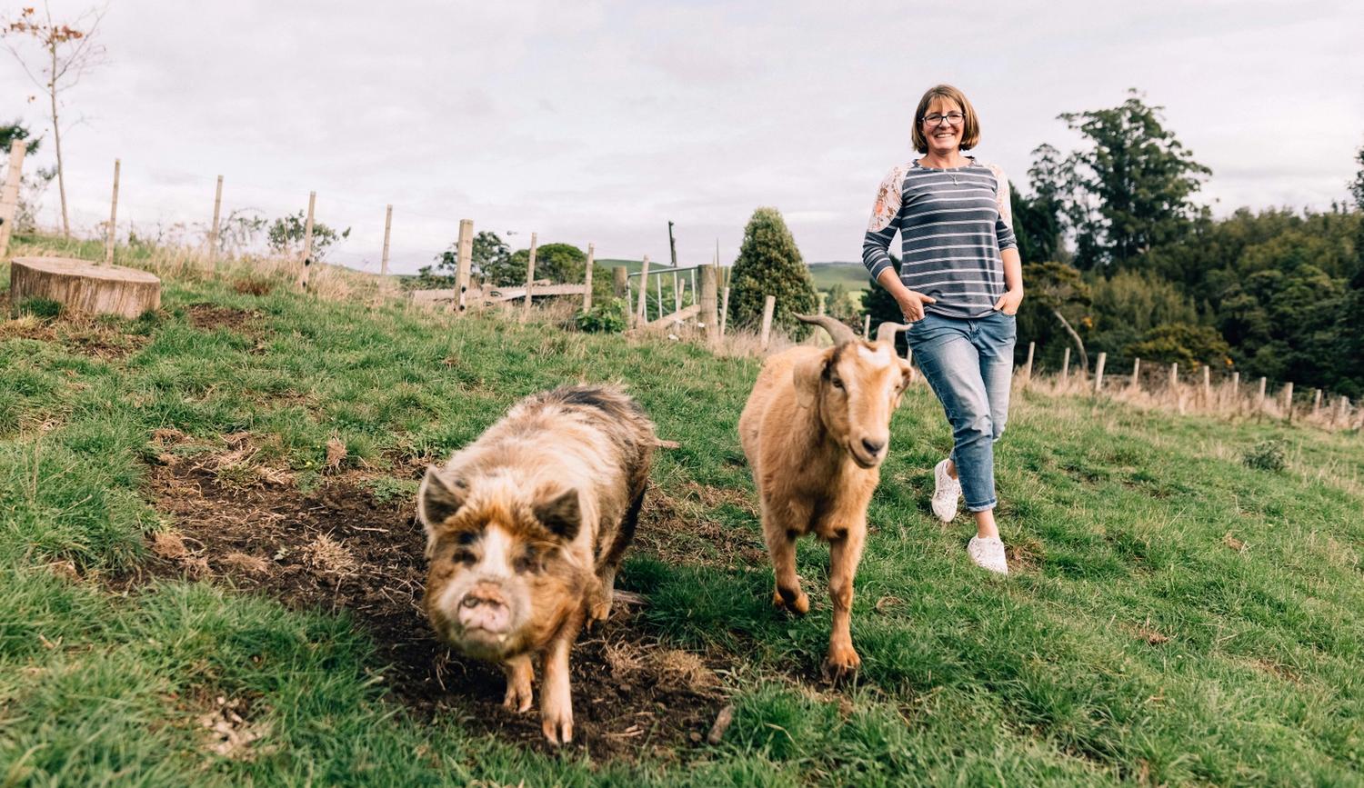 Danielle Hawkins walking on a farm with farm animals by her side