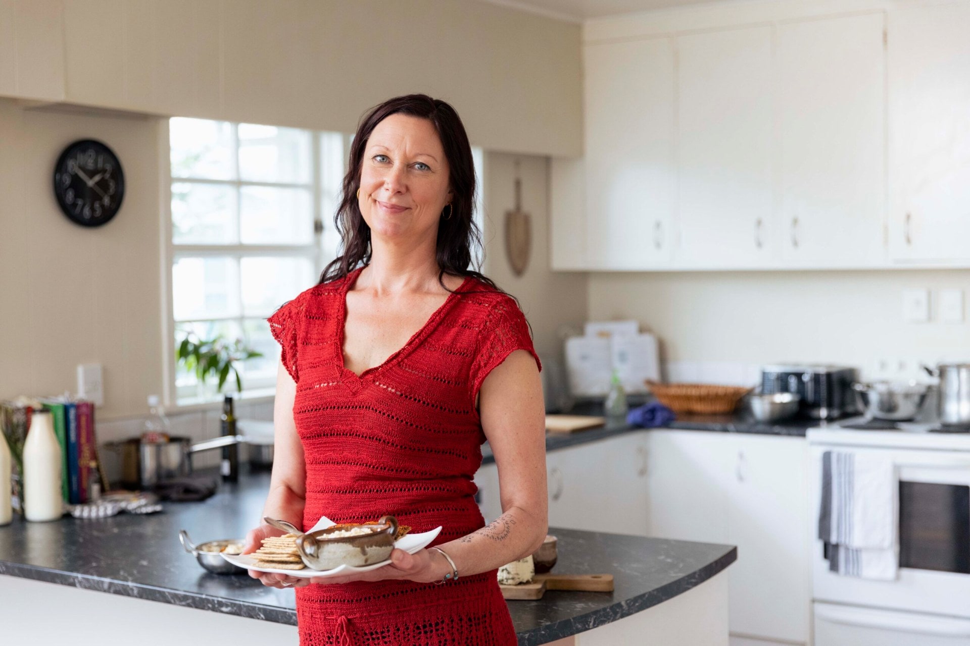 Alexis Murti wearing a red top holding a plate of cheese