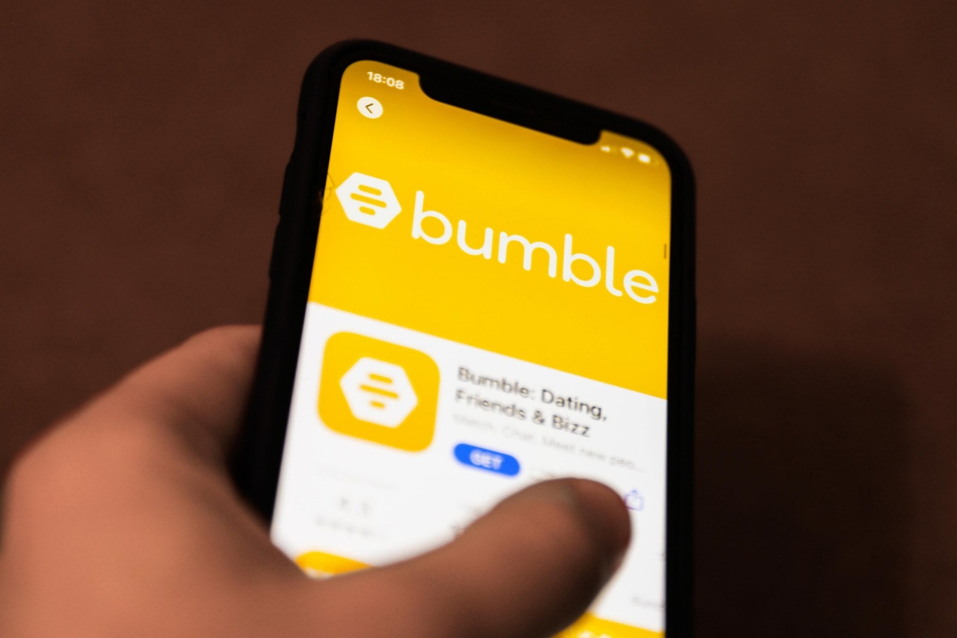 A close up of a hand holding a mobile phone which has the Bumble app open