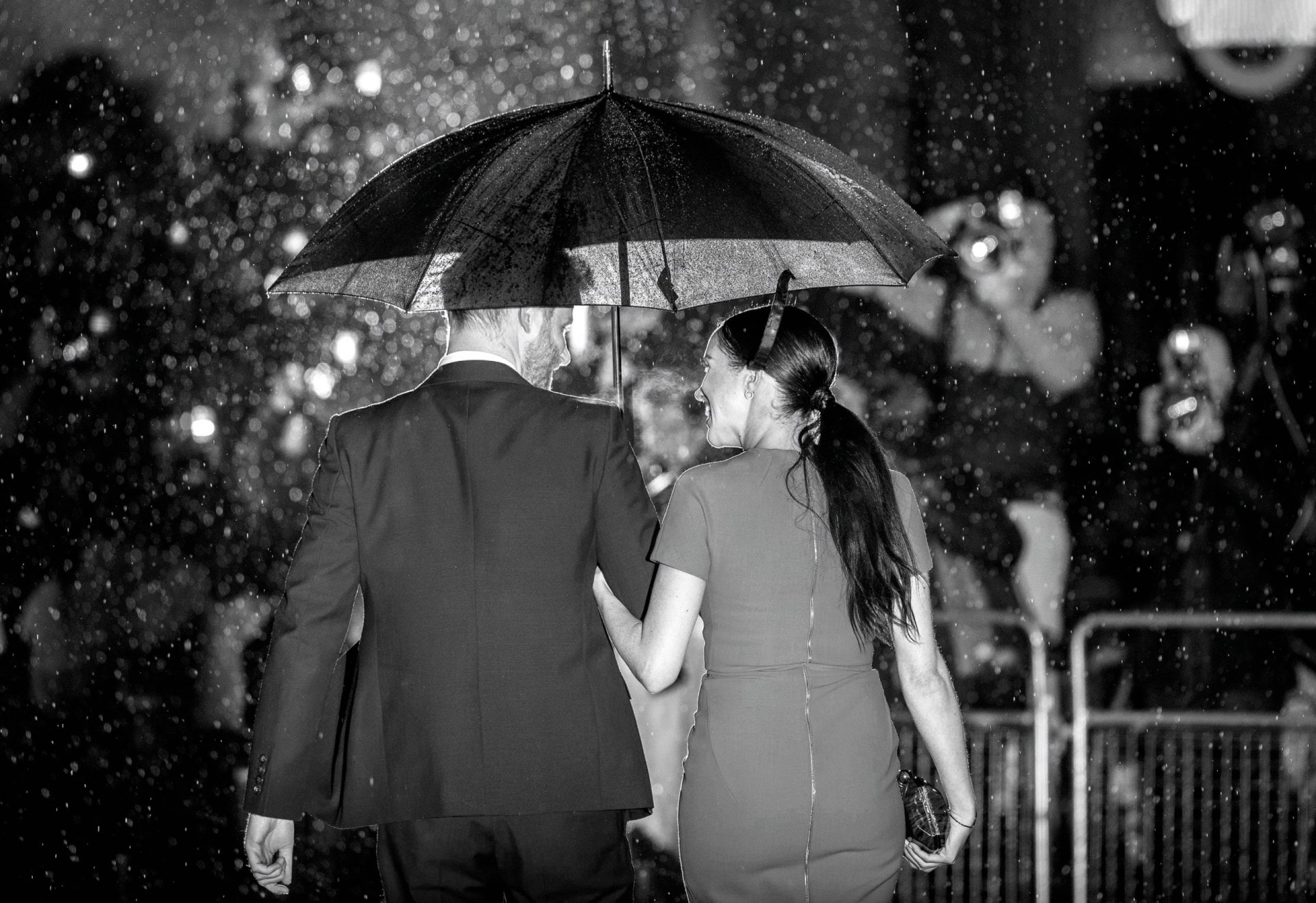 Harry and Meghan in London event standing under umbrella