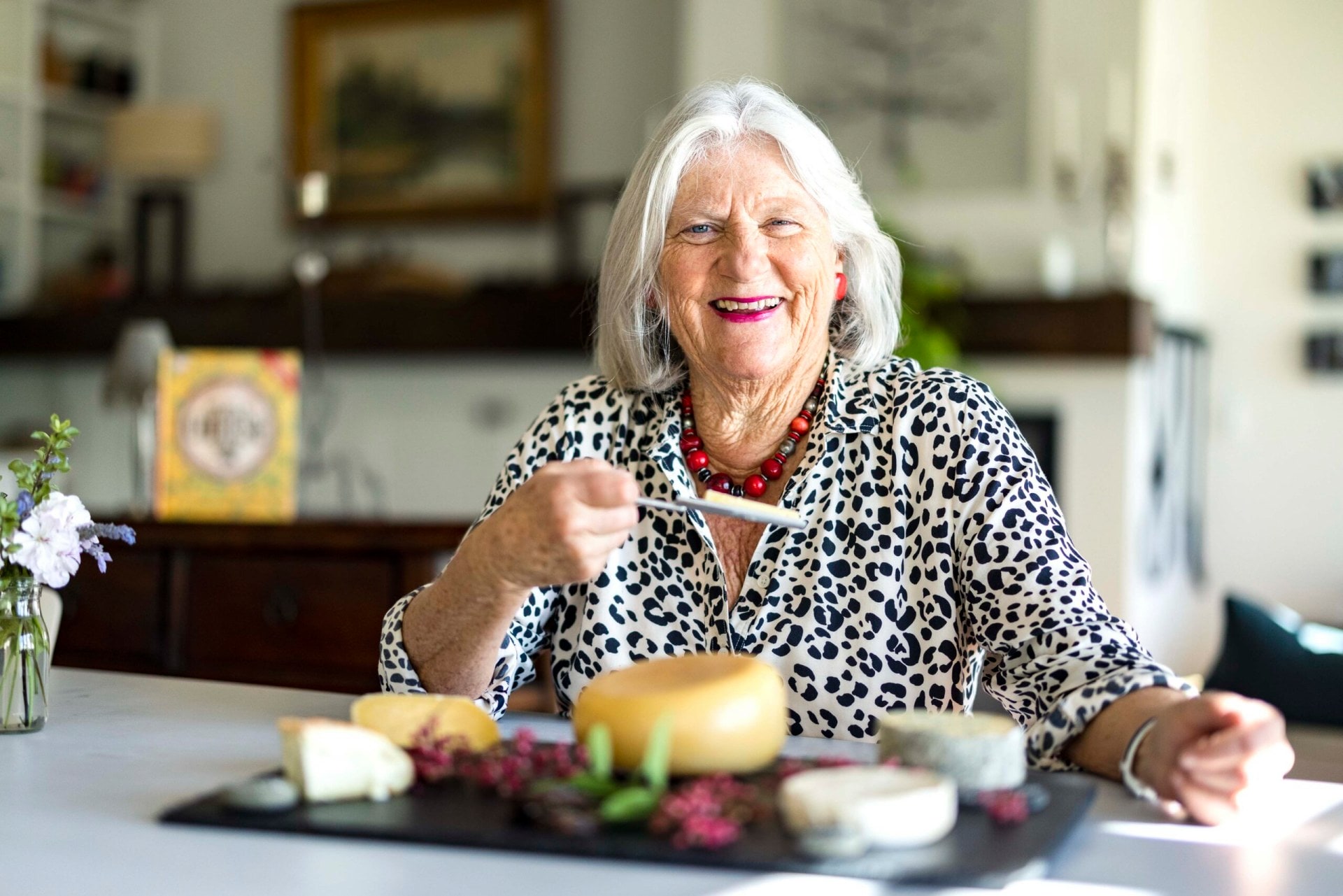 Juliet Harbutt in a leopard print top sitting in front of a cheese board