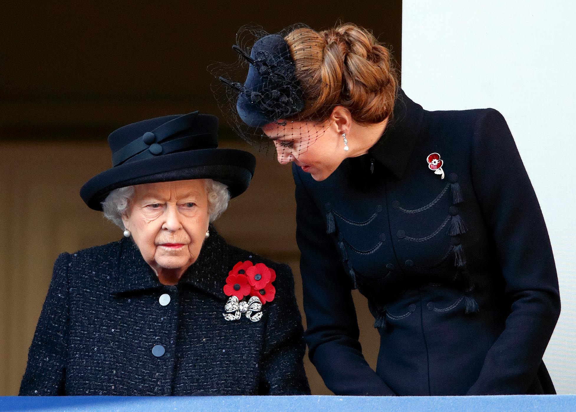 Queen Elizabeth II and Kate Middleton Duchess of Cambridge wearing black coats and poppy pins at Remembrance Day service