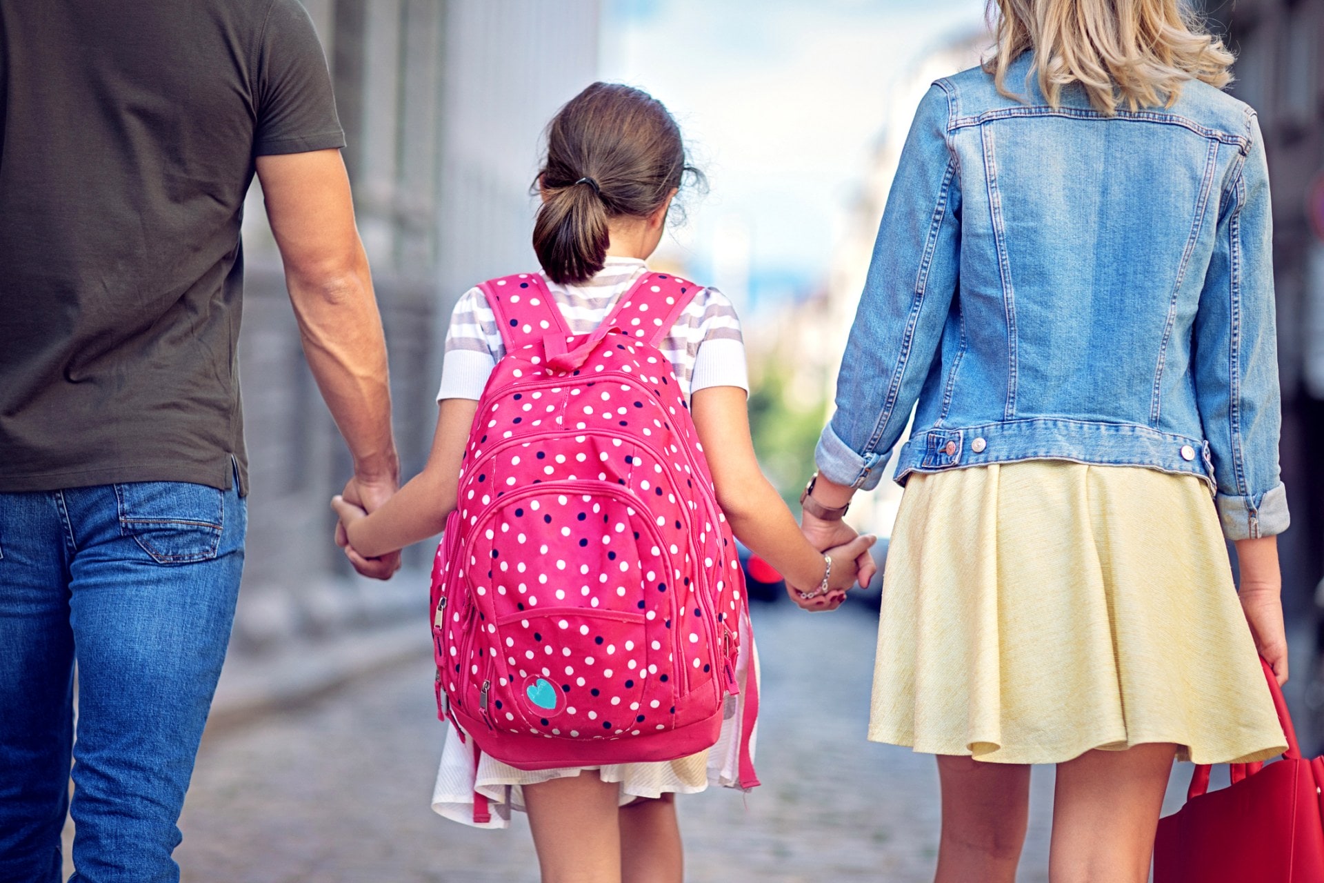 Little girl holding hands with parents 