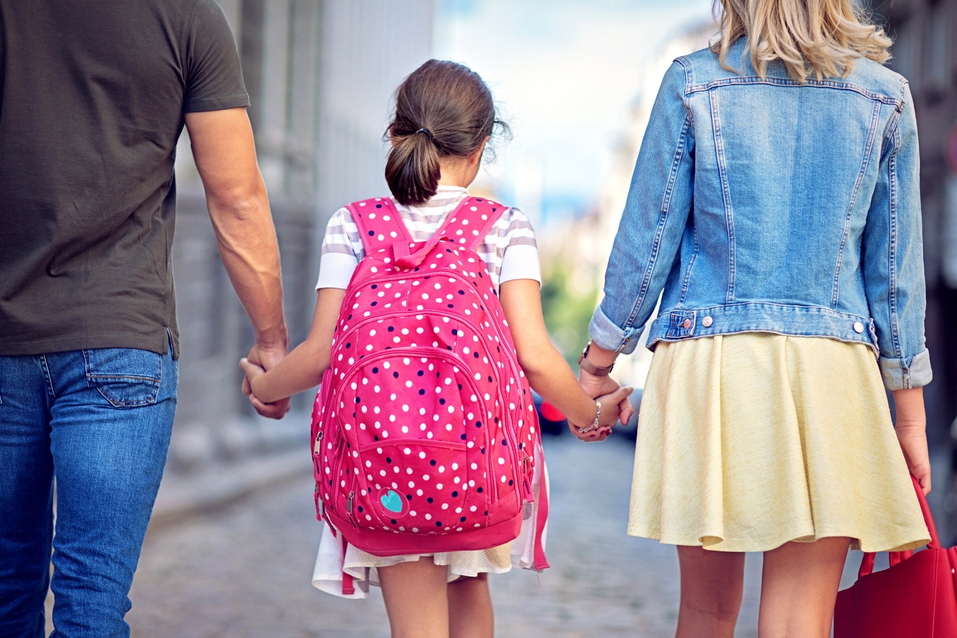 Little girl holding hands with parents