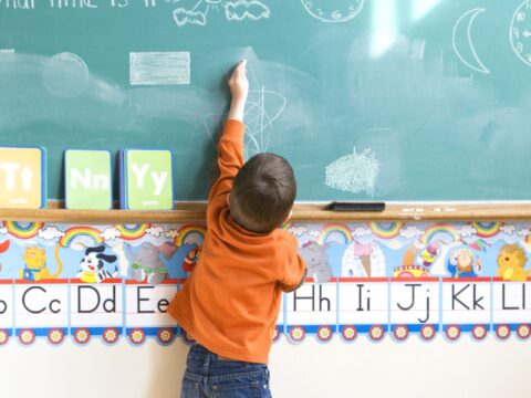 Little boy drawing on chalkboard at school