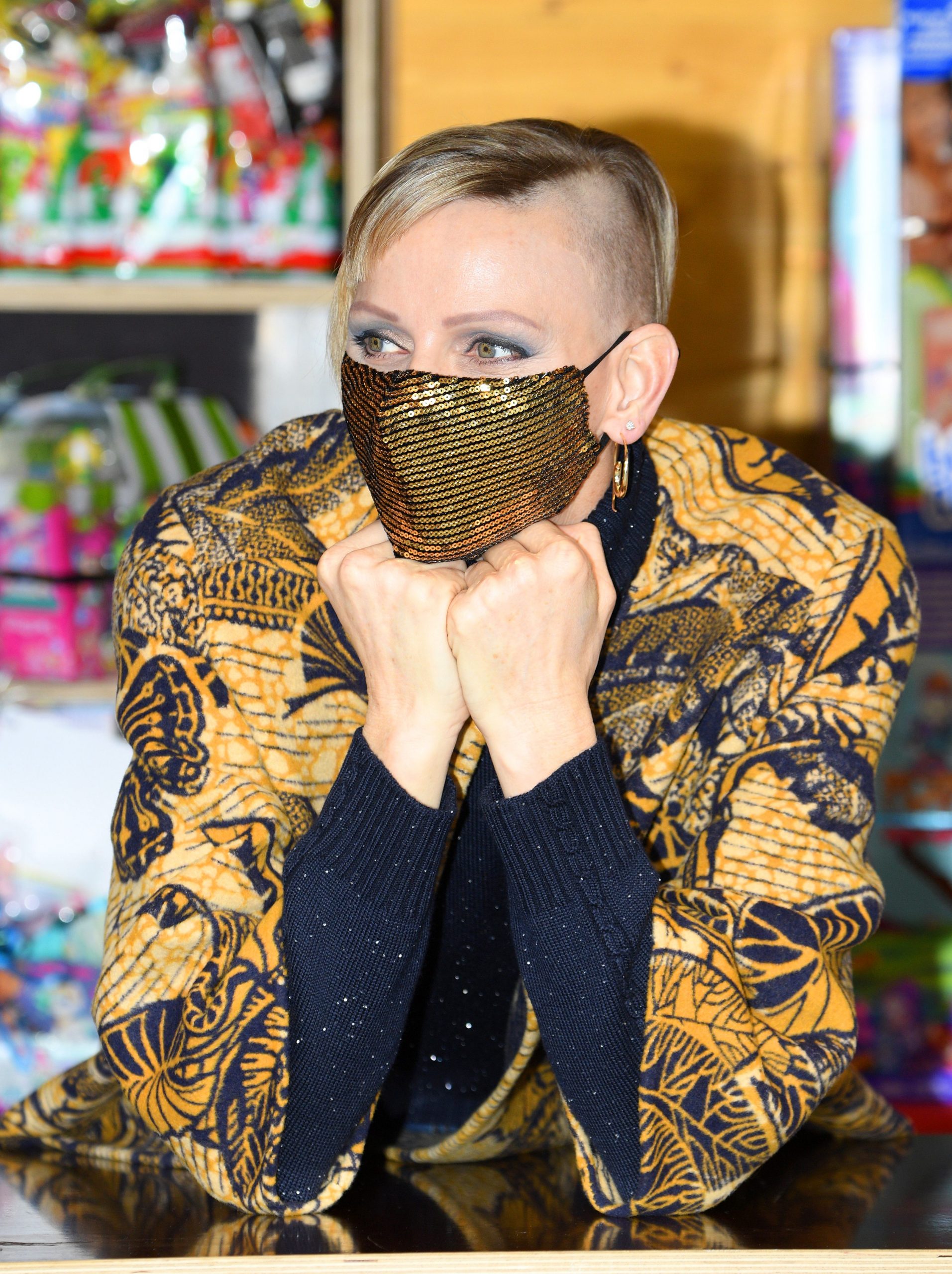 Princess Charlene wearing yellow and black jacket and face mask