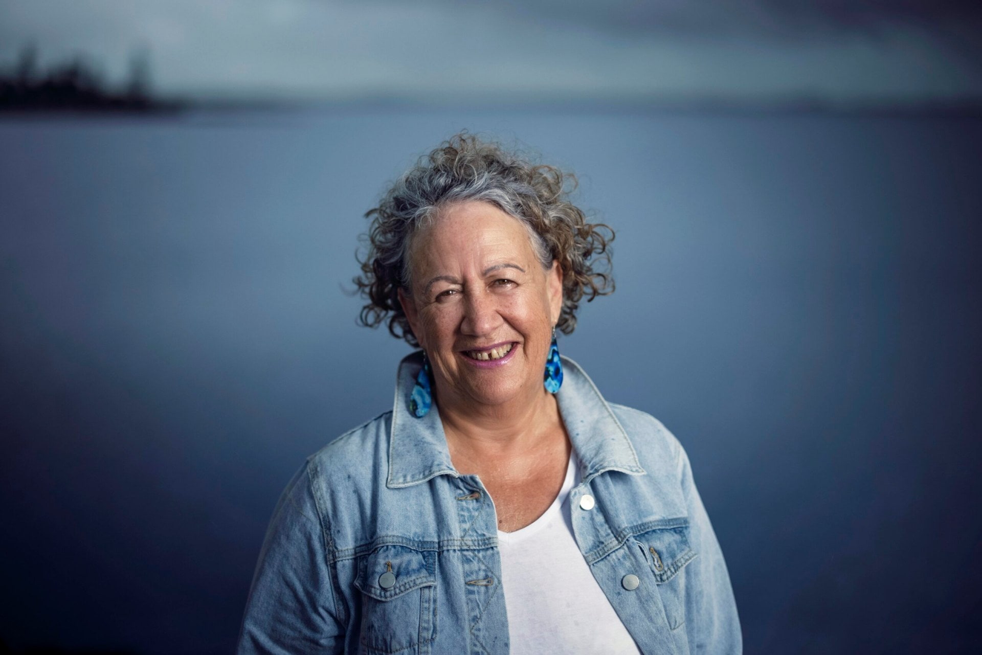 Sharon Armstrong wearing blue jacket, white shirt and blue earrings