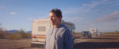 Frances McDormand in Nomadland standing outside an RV