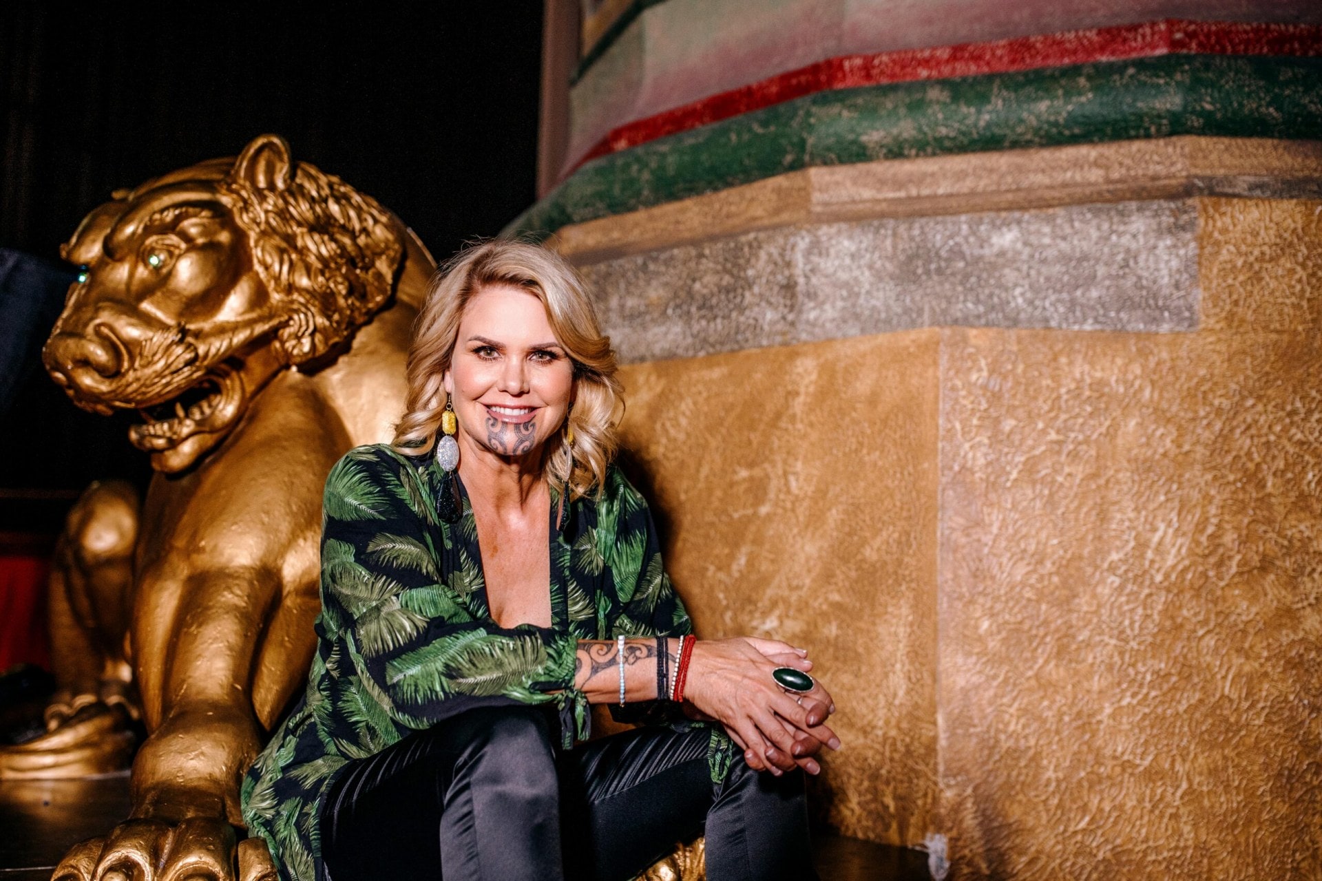 Dr Hinemoa Elder sitting on steps wearing green patterned jacket