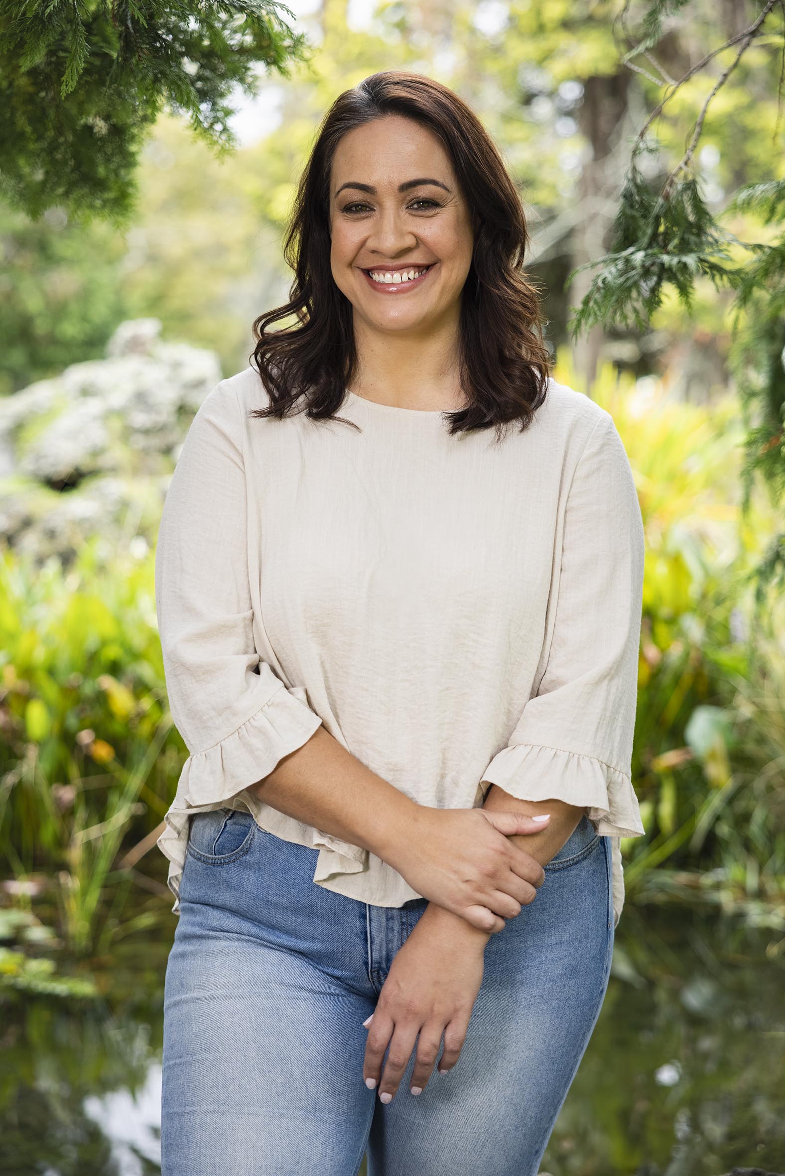 Stacey Leilua smiling and wearing a white top and blue jeans 