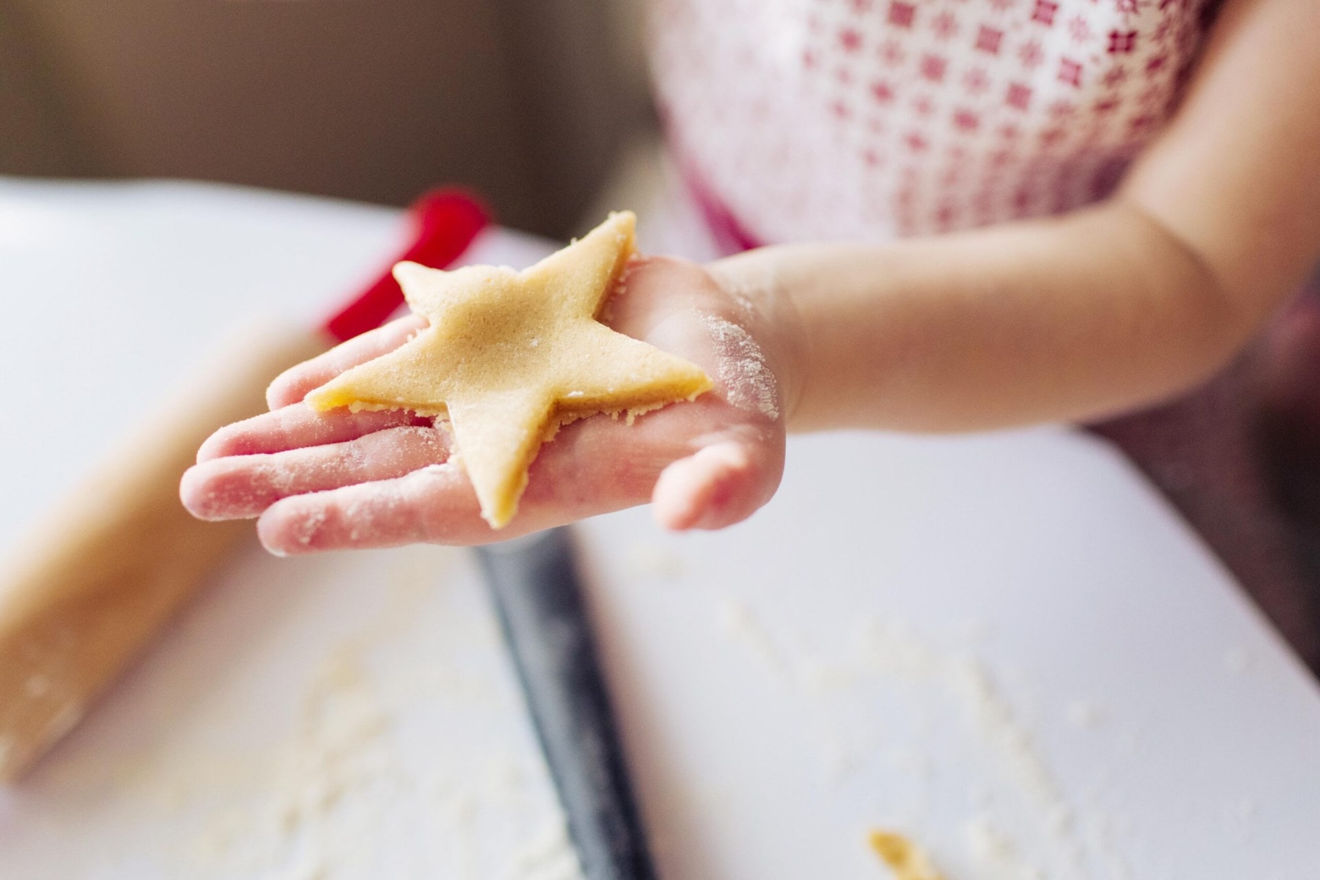 A child's hand holding a dough star biscuit in hand