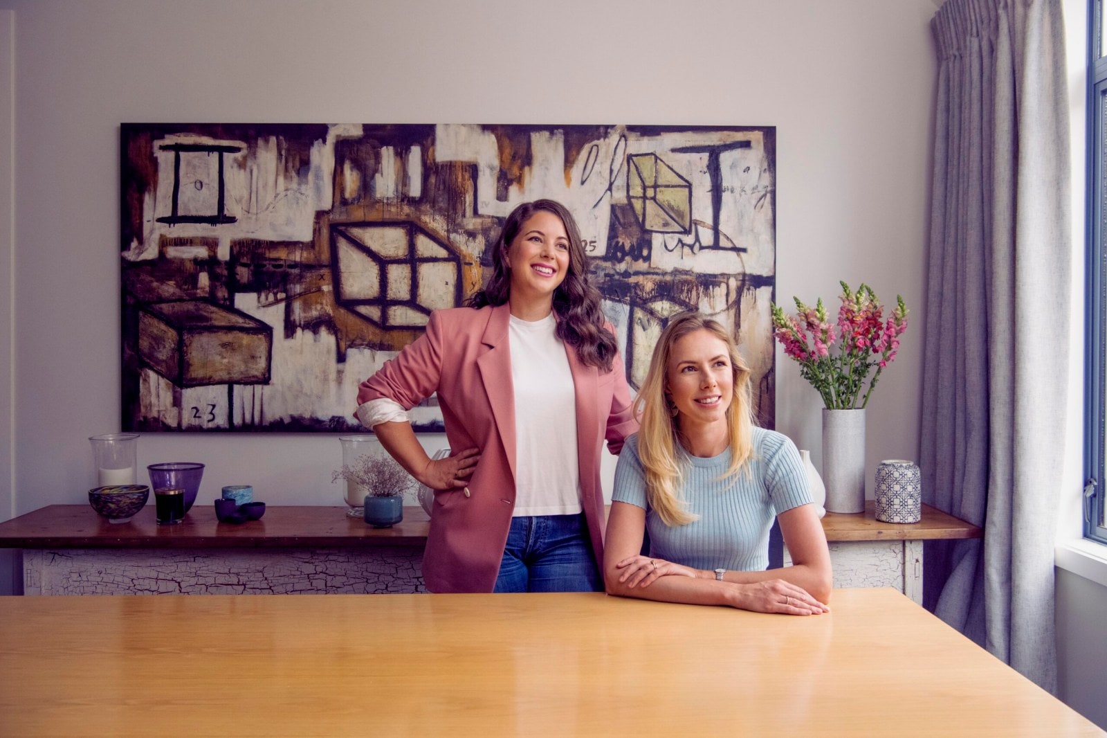 Brooke Roberts a Sonya Williams z Sharesies sedí spolu u hnědého stolu