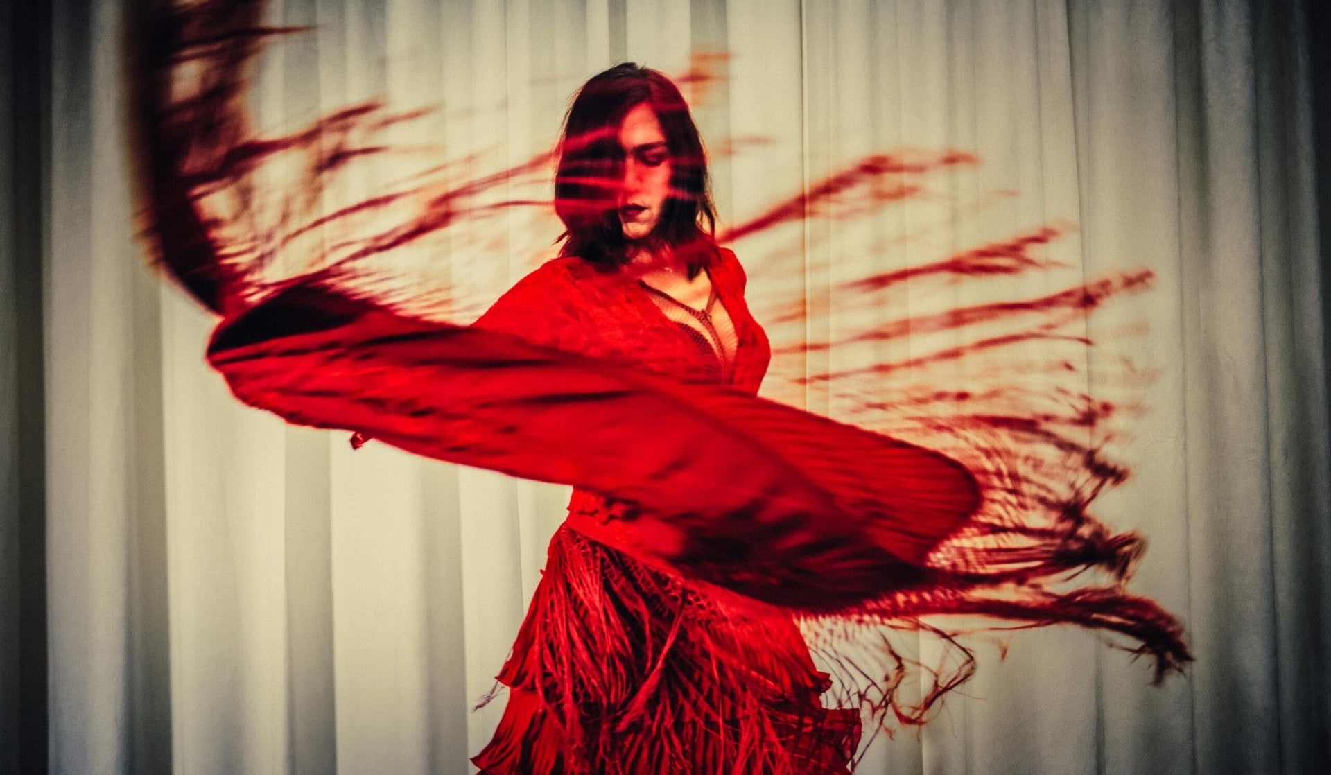 woman in fringed red dress spinning so the fringe is flying