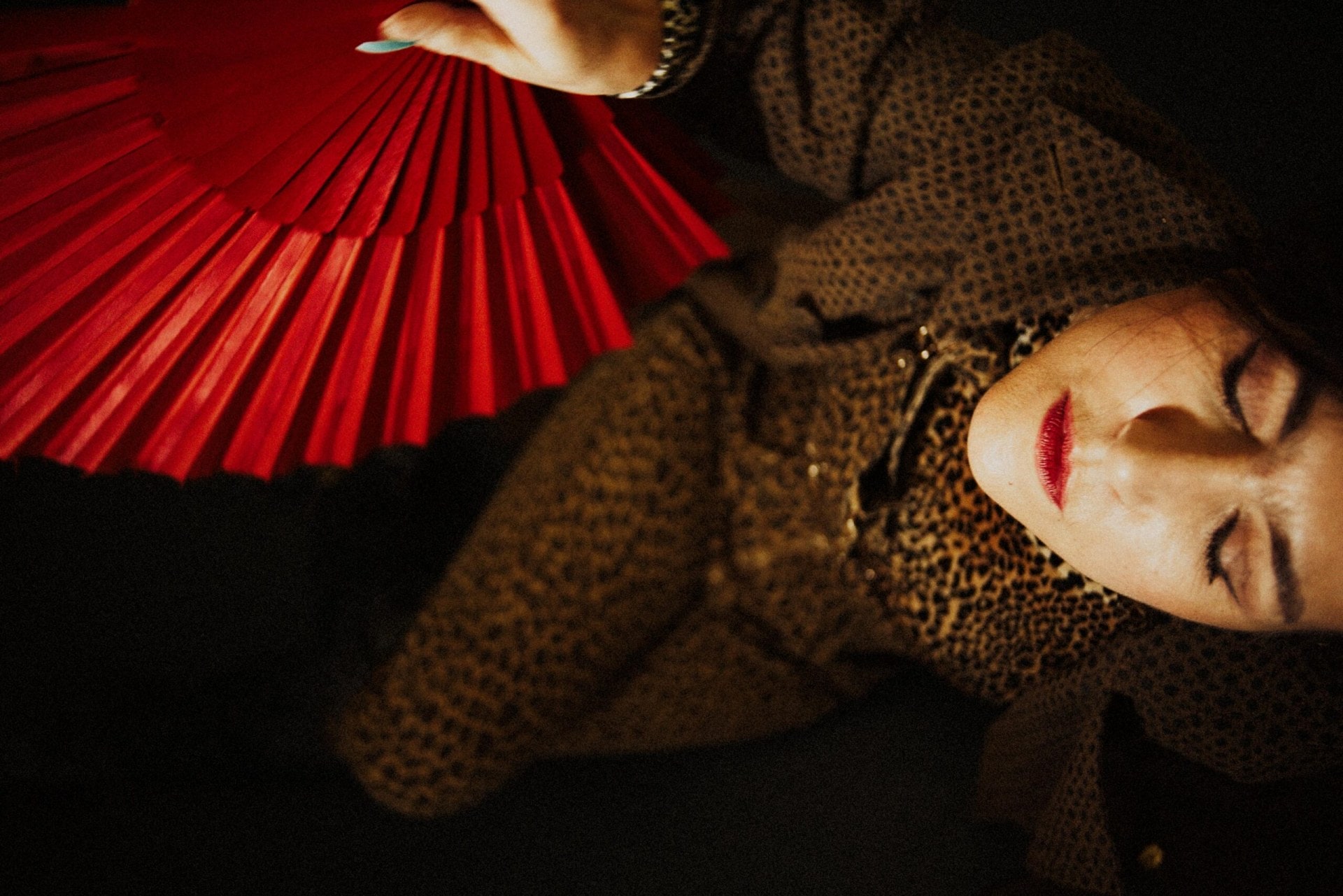 woman in leopard print holding a red fan