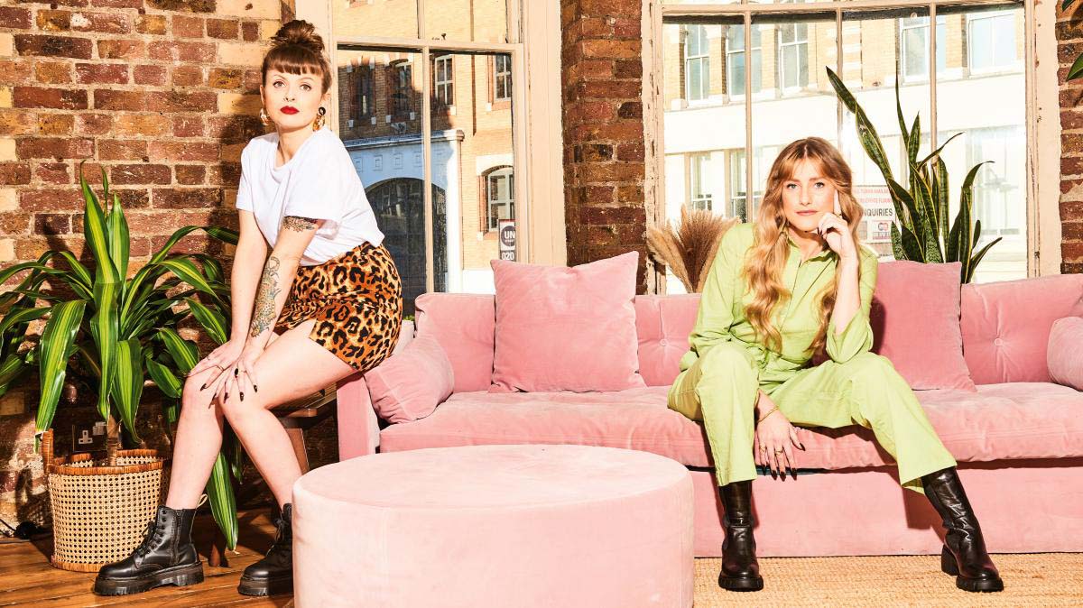 two young women sitting on a pink couch
