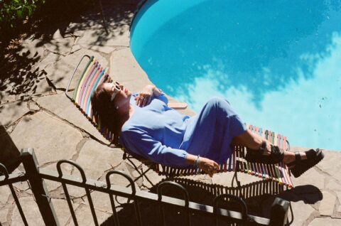 A woman lying on a recliner next to a pool