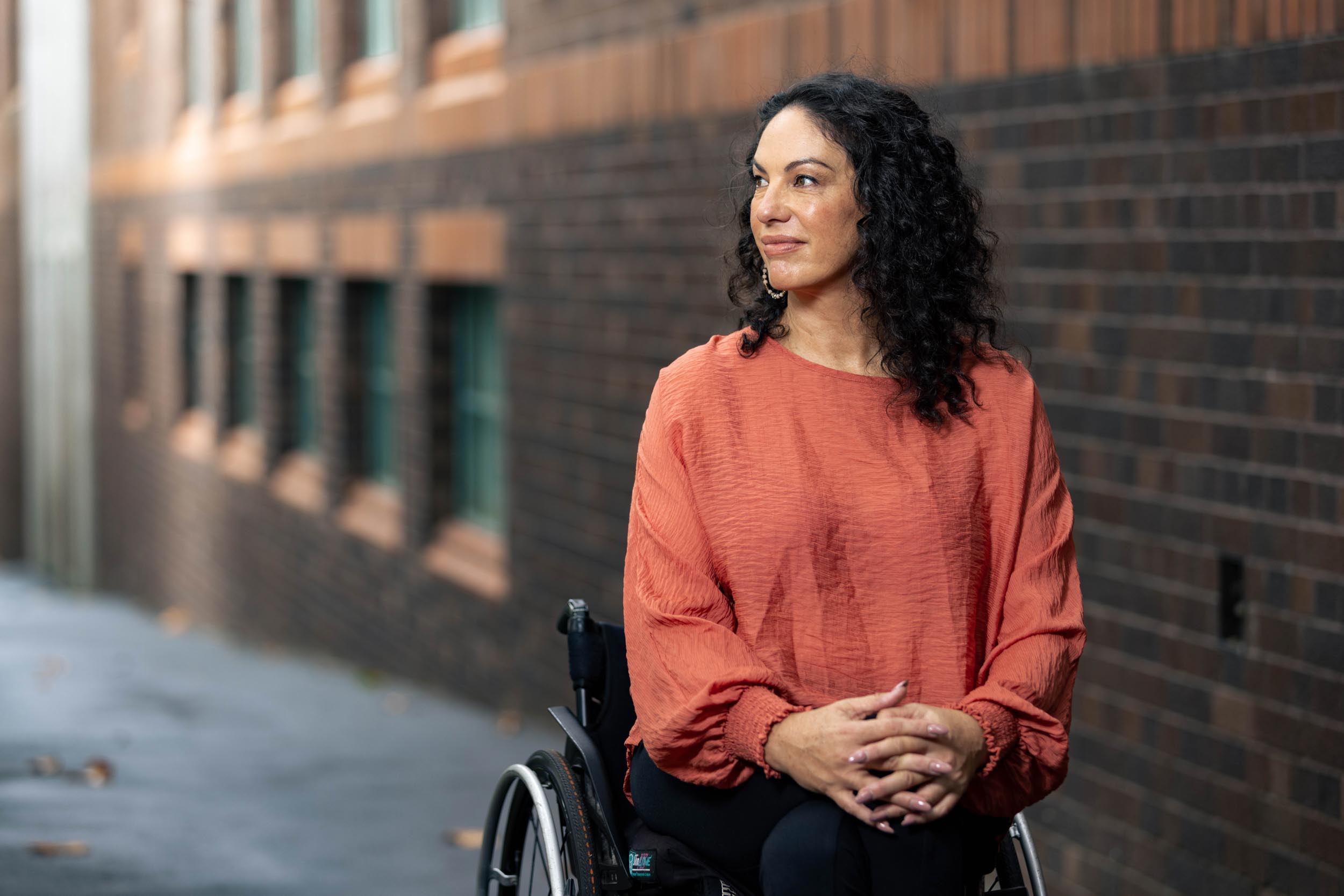 Paula in an orange top in her wheelchair