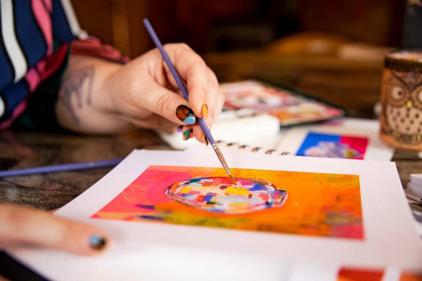 A woman's hand painting a colourful picture