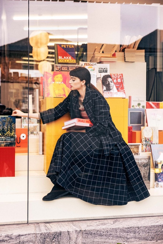 a model wearing a plaid shirt and skirt in a bookstore window