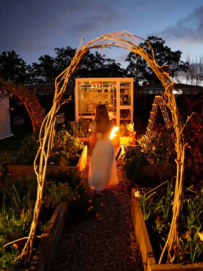 Rachel Clare in a white dress walking through her garden