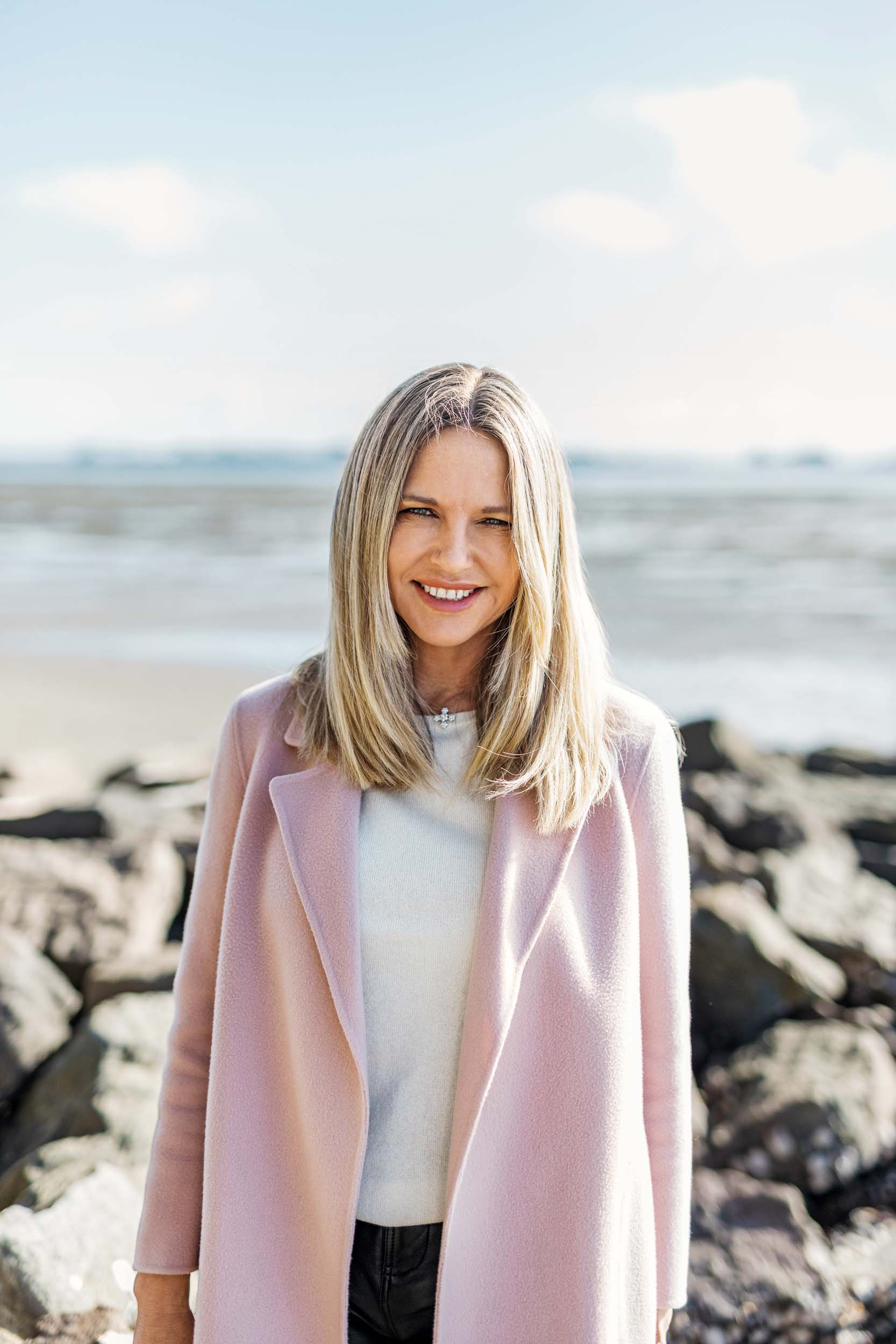 Sharon Hunter in a pink coat on a beach