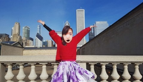Li-Ming wearing a mask of her own face standing on a rooftop