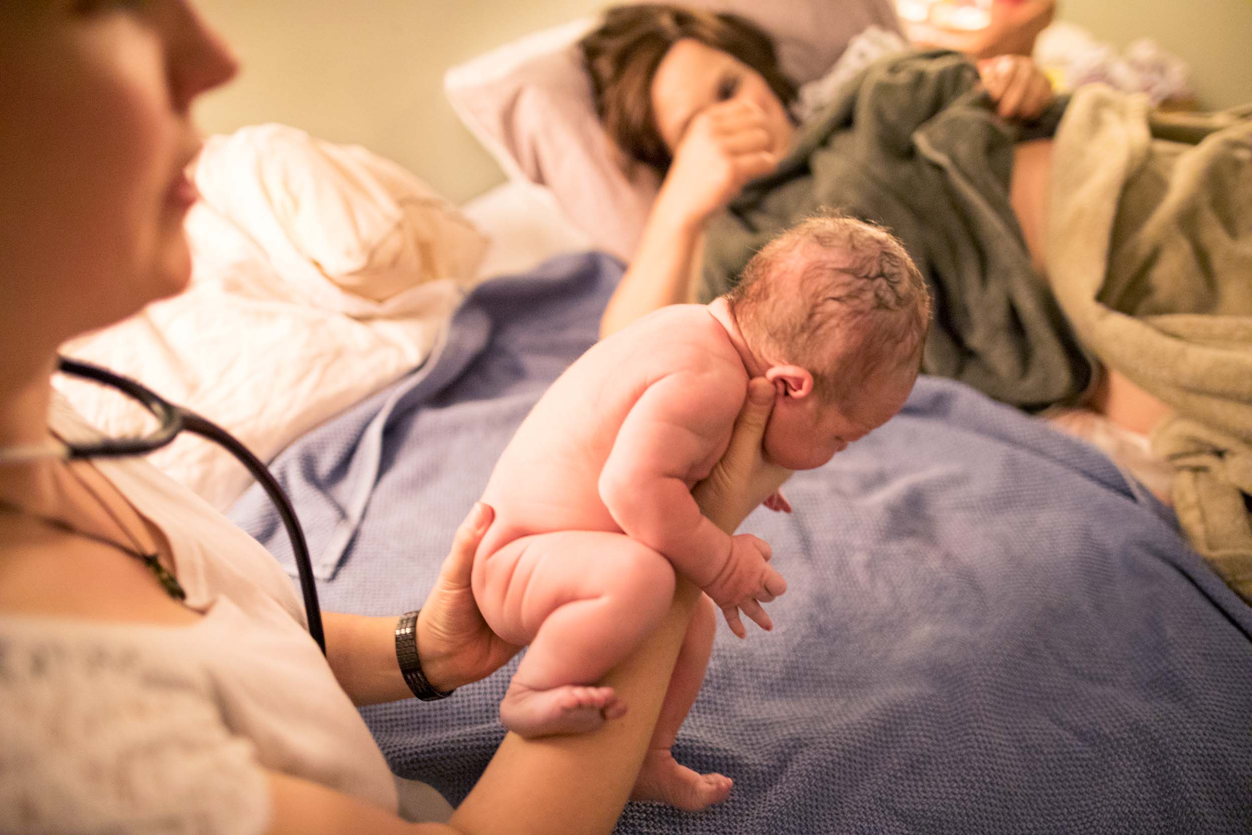 a newborn baby held by a midwife