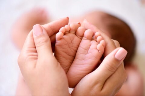 Mother holding tiny foot of newborn baby