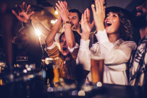 Group of friends cheering with beer in a pub
