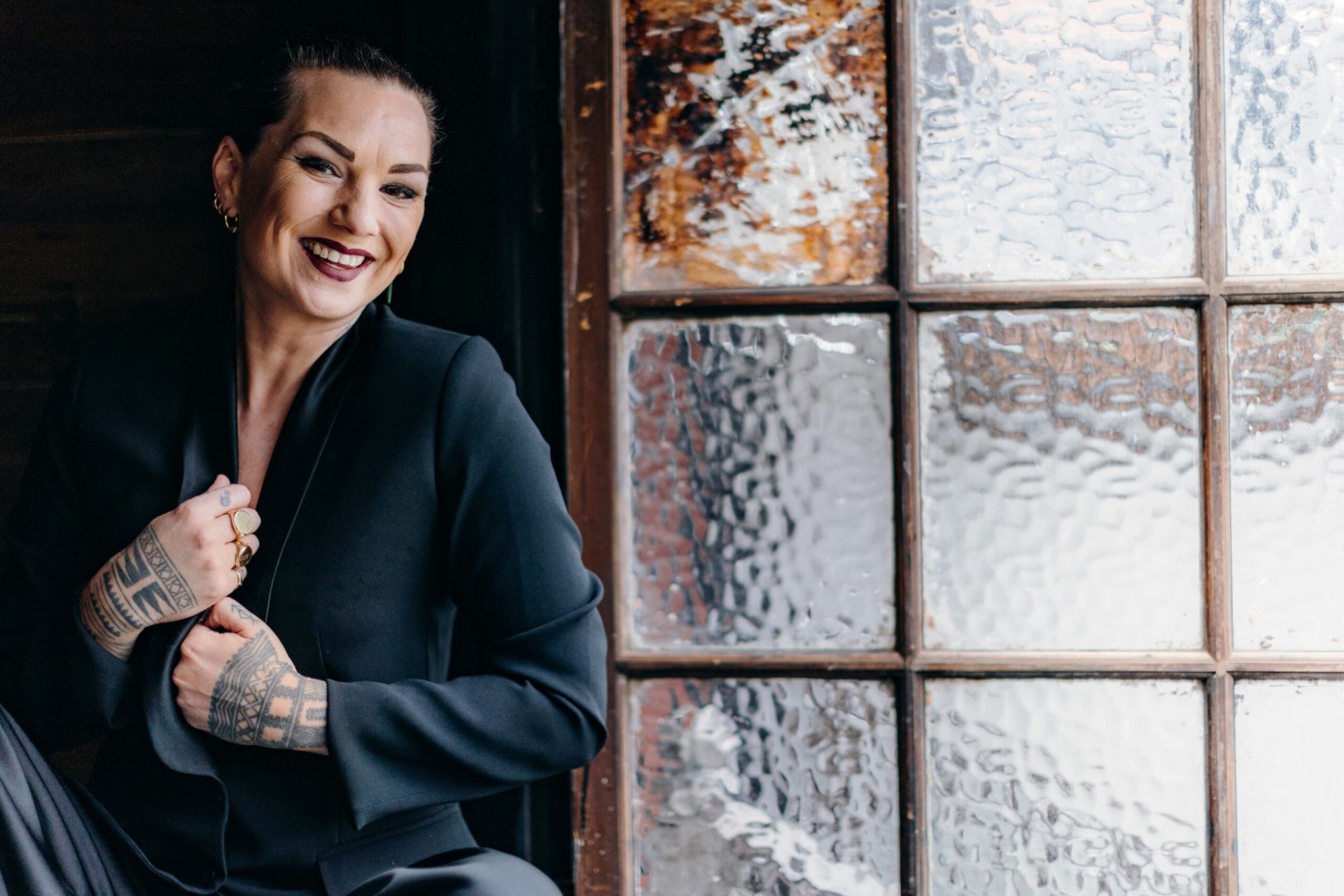 Hollie Smith in a charcoal suit sitting in front of a window