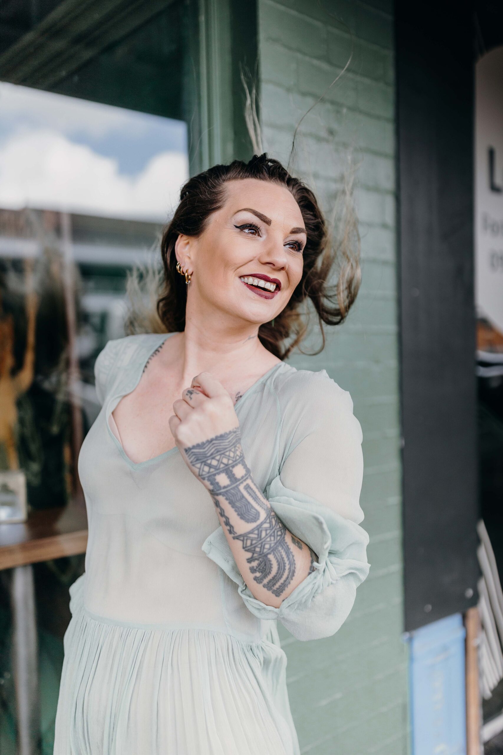 Hollie Smith in a pale green dress smiling and her hair whipping in the wind