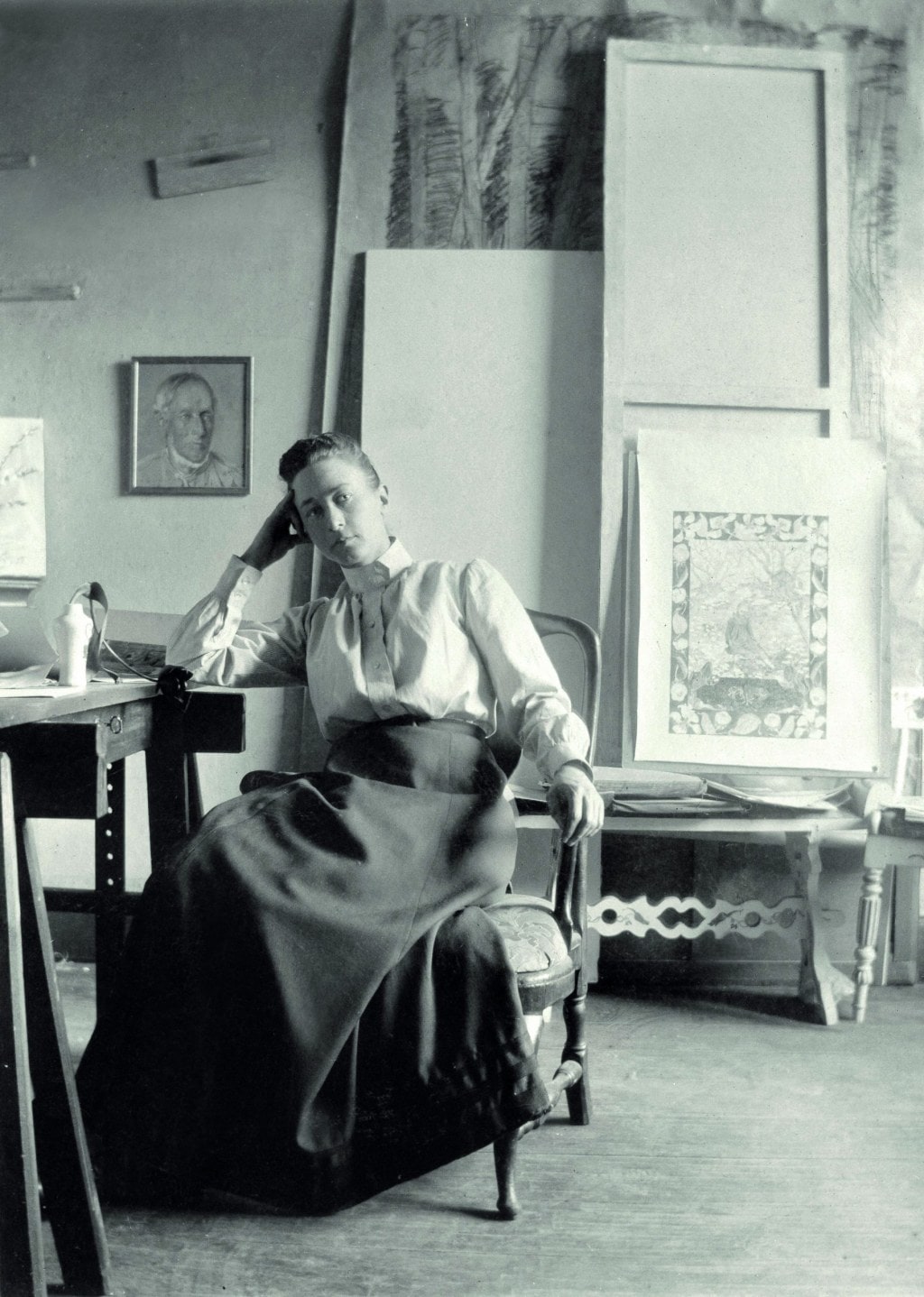 Black and white image of Hilma af Klint sitting in a chair in an art studio
