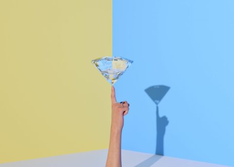 a diamond balancing on a finger in front of a blue and yellow background