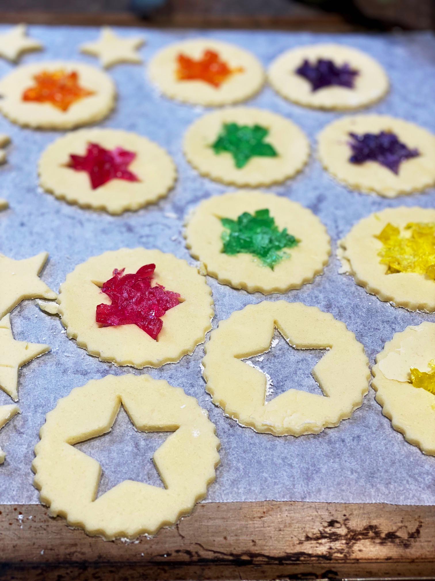 Round biscuits with star cut outs and colourful crushed candy in the middle