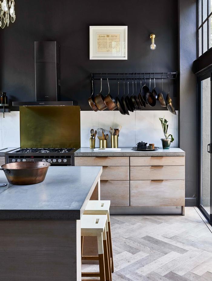 A grey tiled kitchen with wooden drawers and black walls