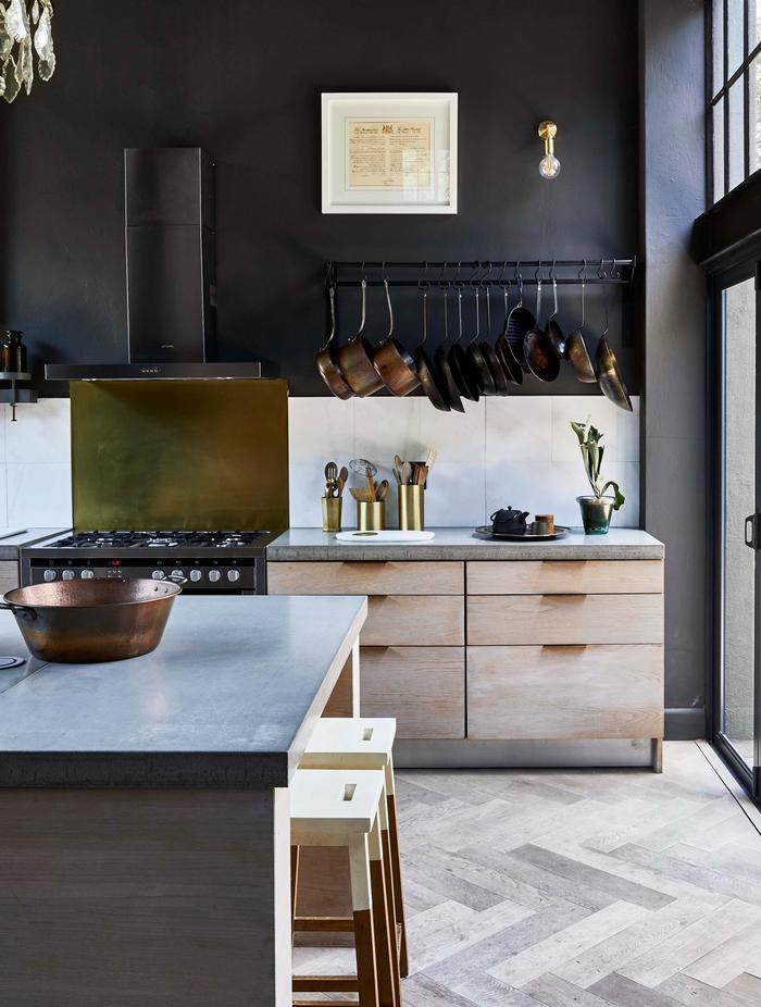 A grey tiled kitchen with wooden drawers and black walls 