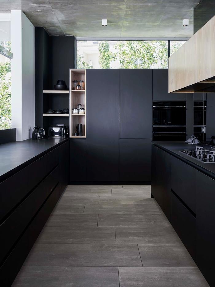 A black kitchen with light wood floors