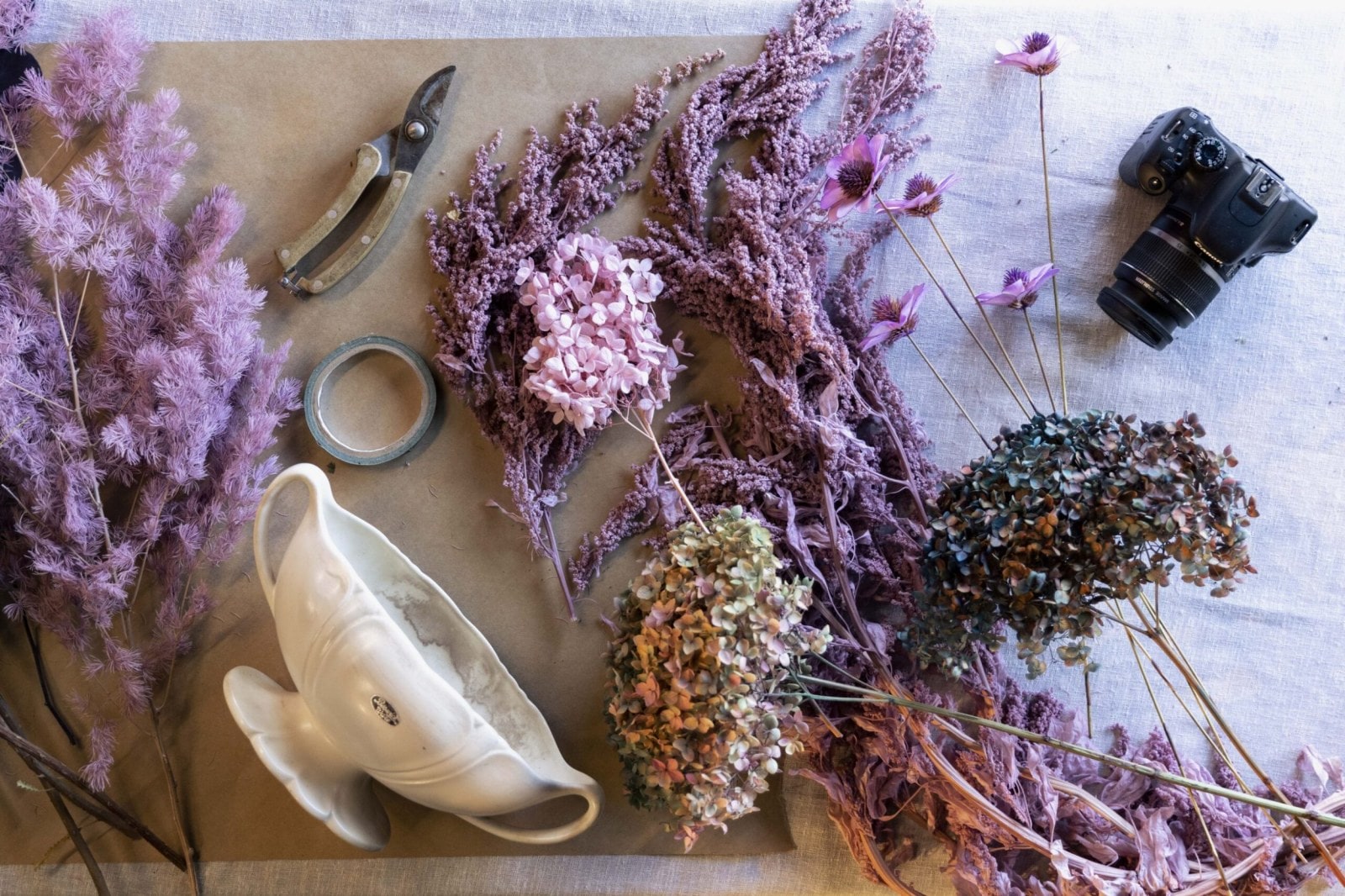 Flatlay z Beswick květinové urny, pásky a růžových a fialových sušených květin