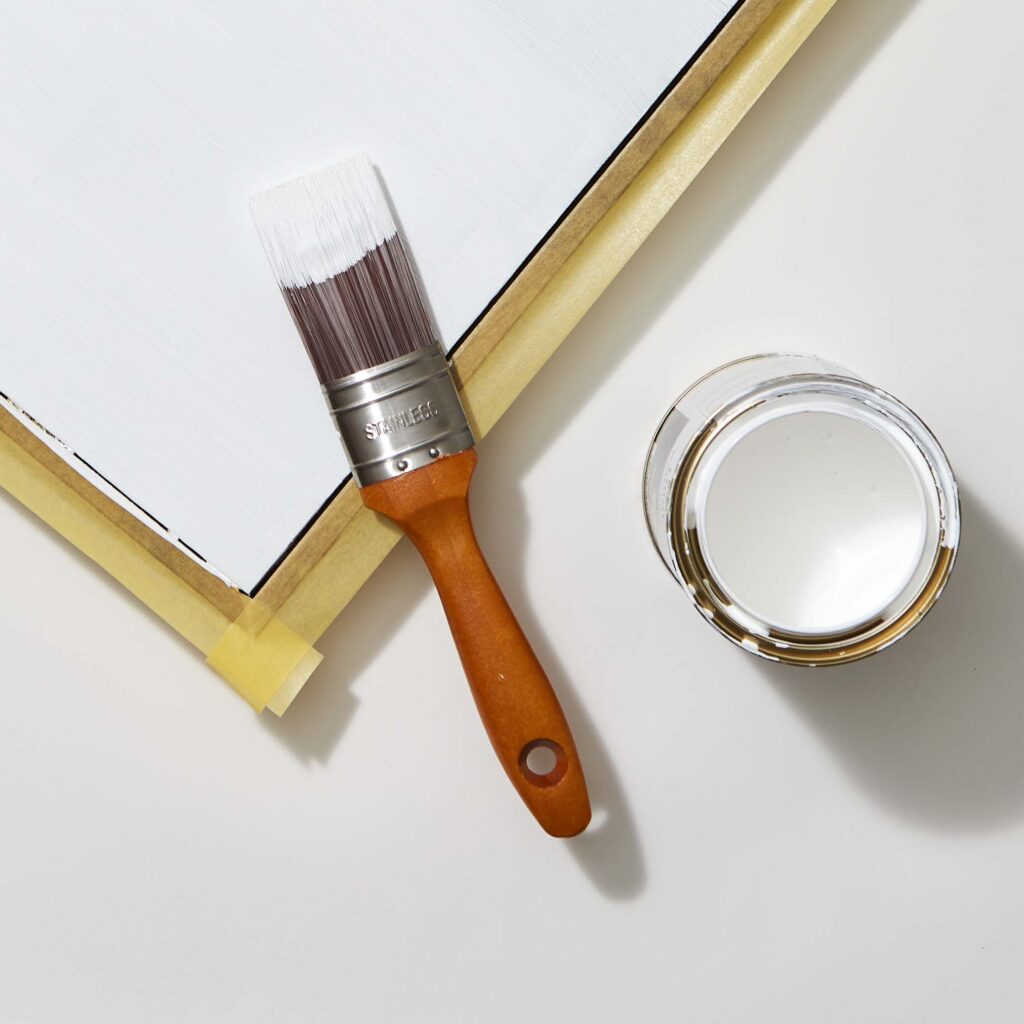A white table with a white Resene paint and a paint brush on top