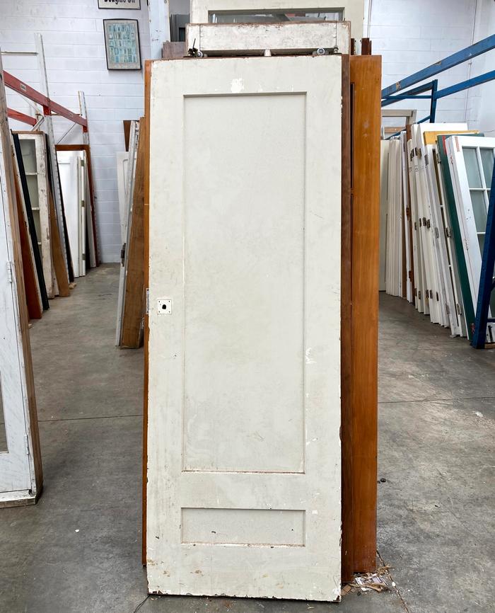 Rows of assorted old doors stacked upright in large concrete room