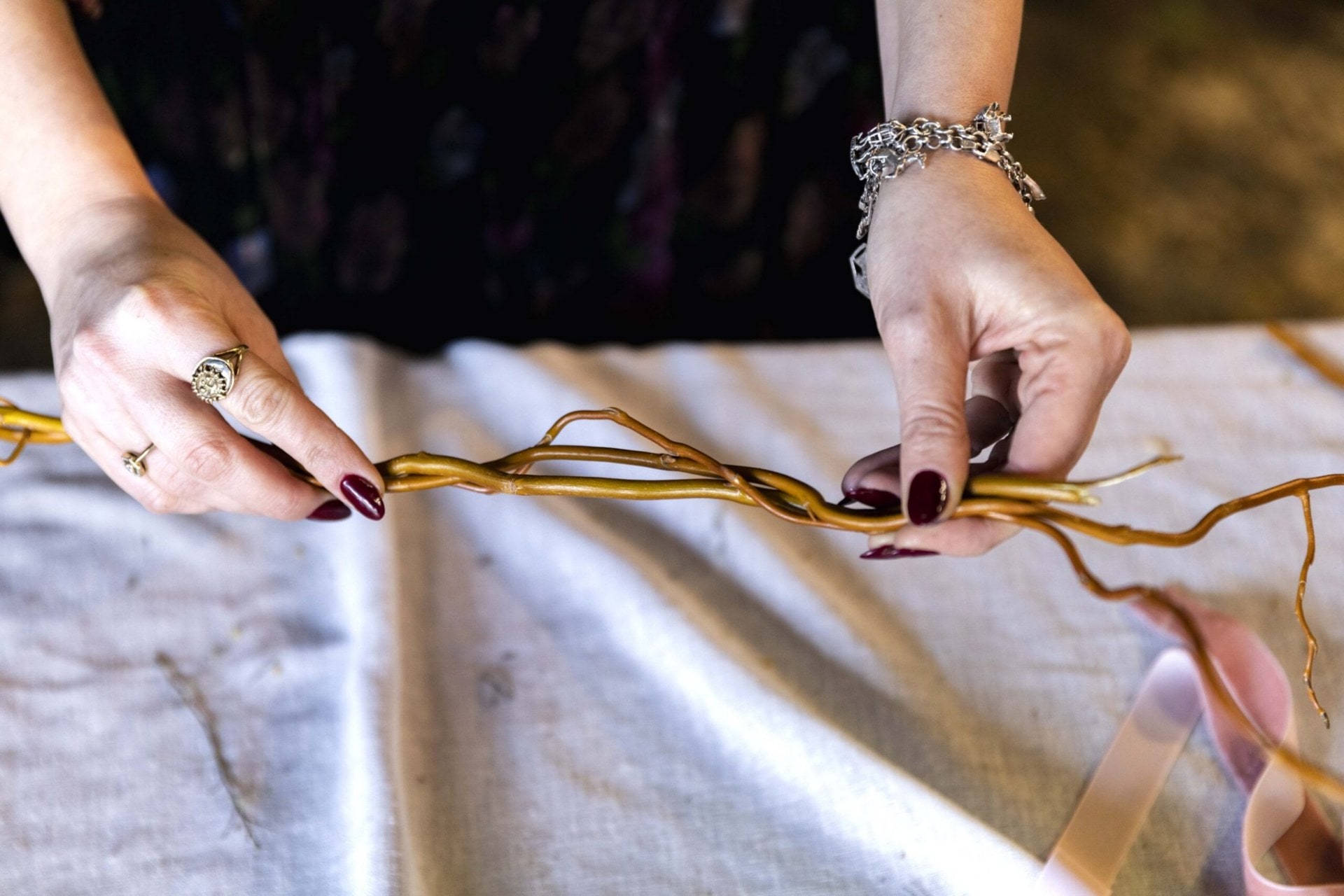 A pair of hands twisting two willow stems together