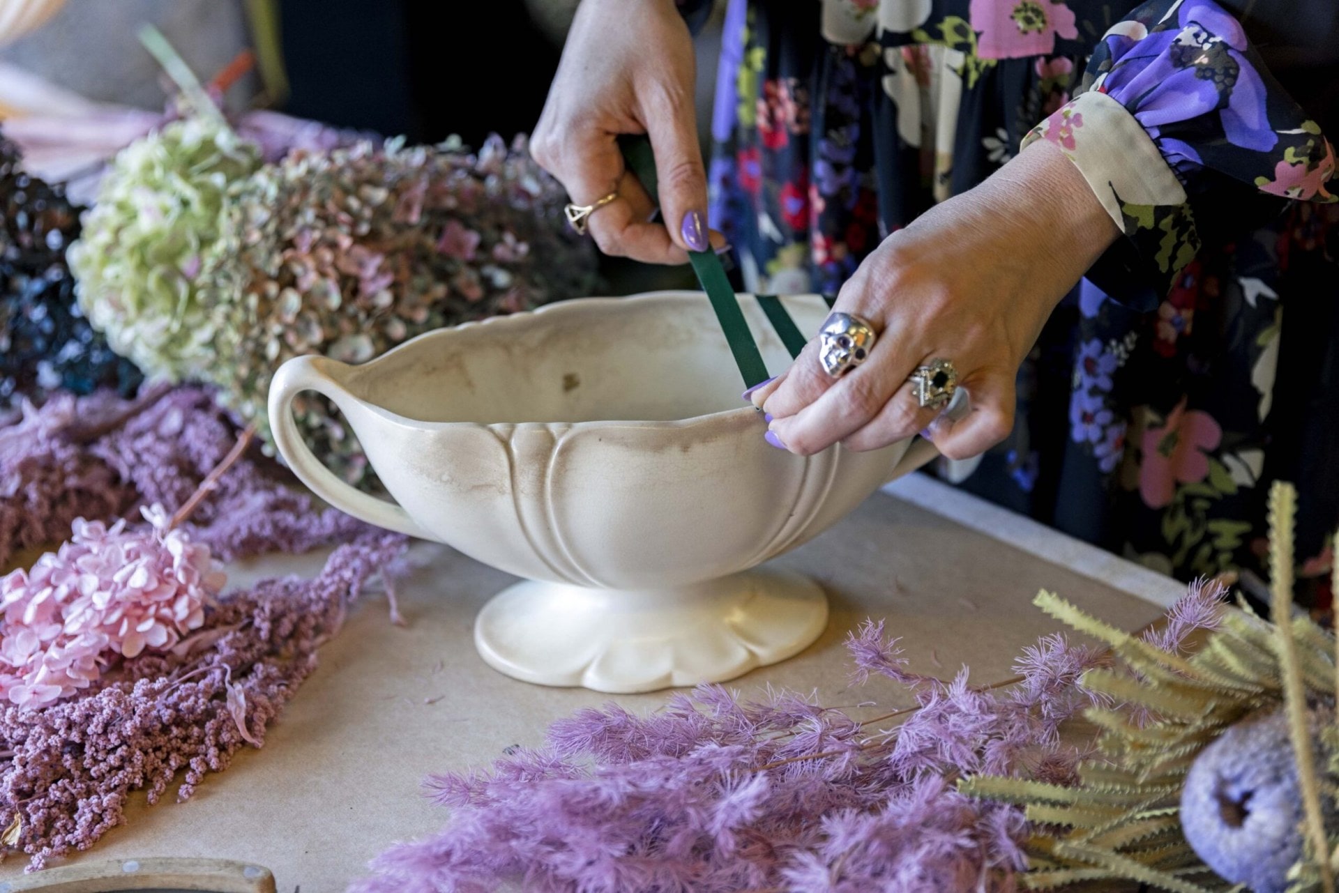 Woman's hands applying green tape on Beswick flower urn