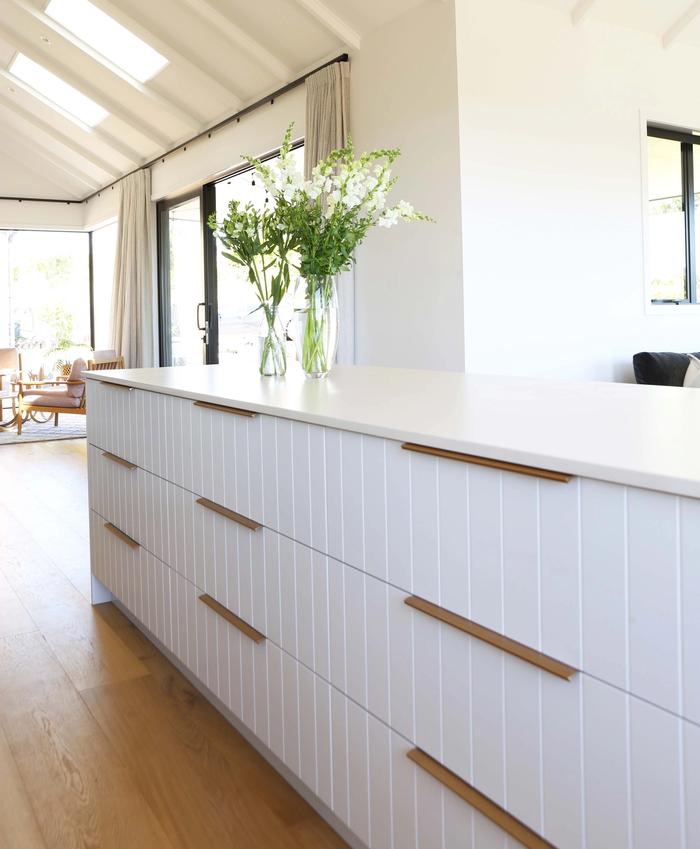 white kitchen with long brass pull handles on the cabinets