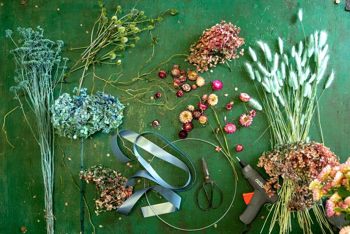 Dried flowers and metal loop lying on green background