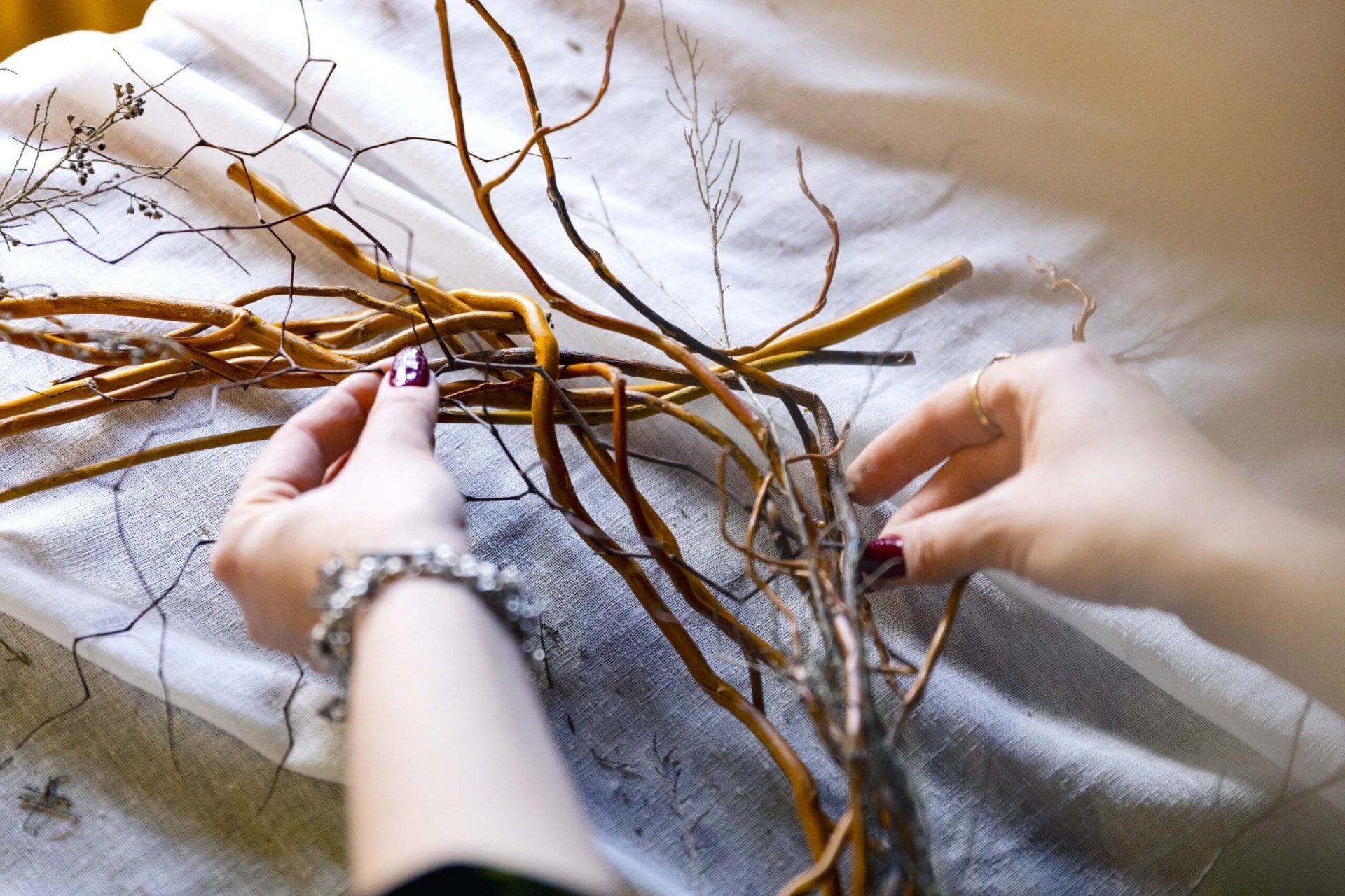 Flower stems being inserted into a wreath made out of willow stems