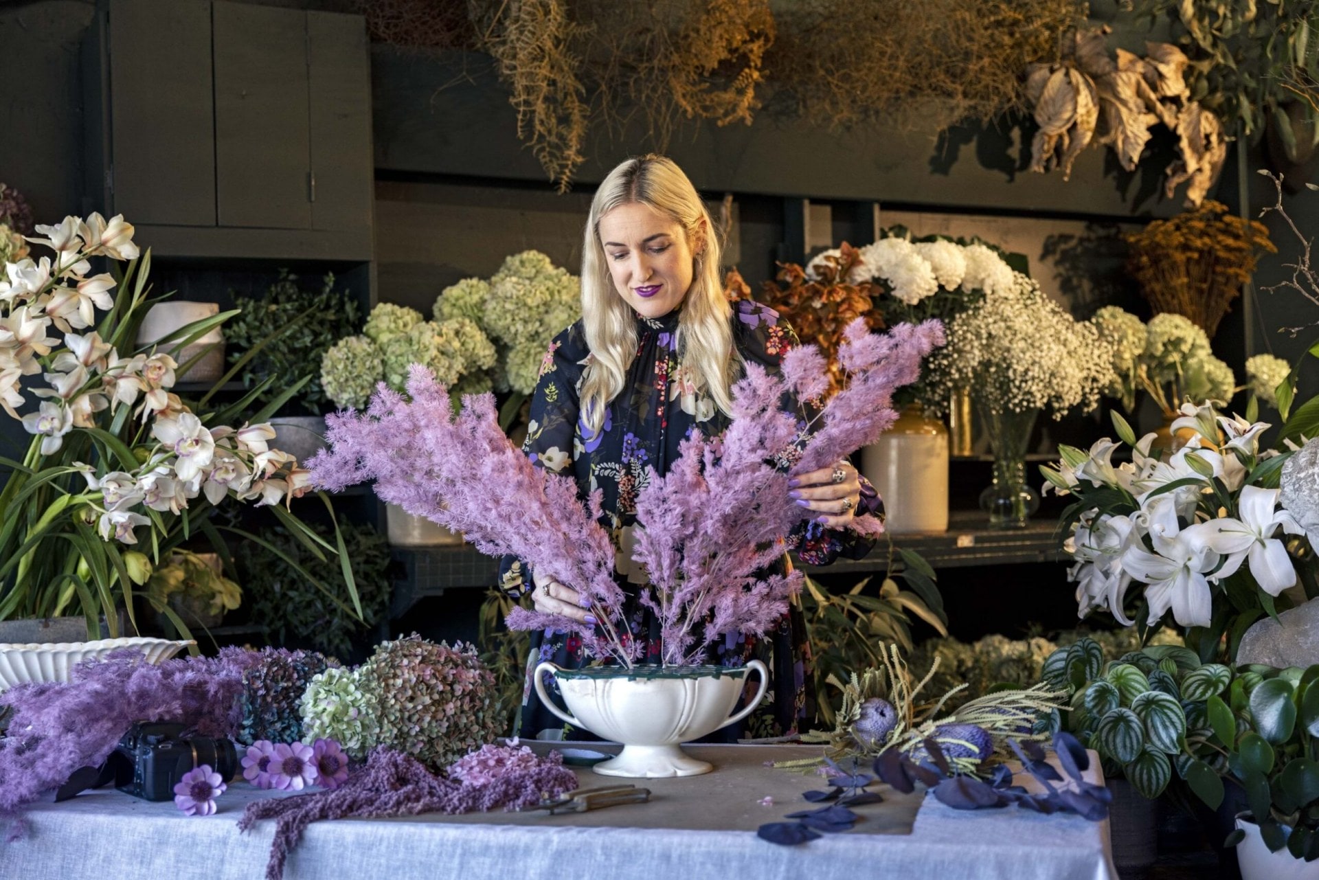 Georgie Malyon placing short purple fried flowers into a Beswick flower urn