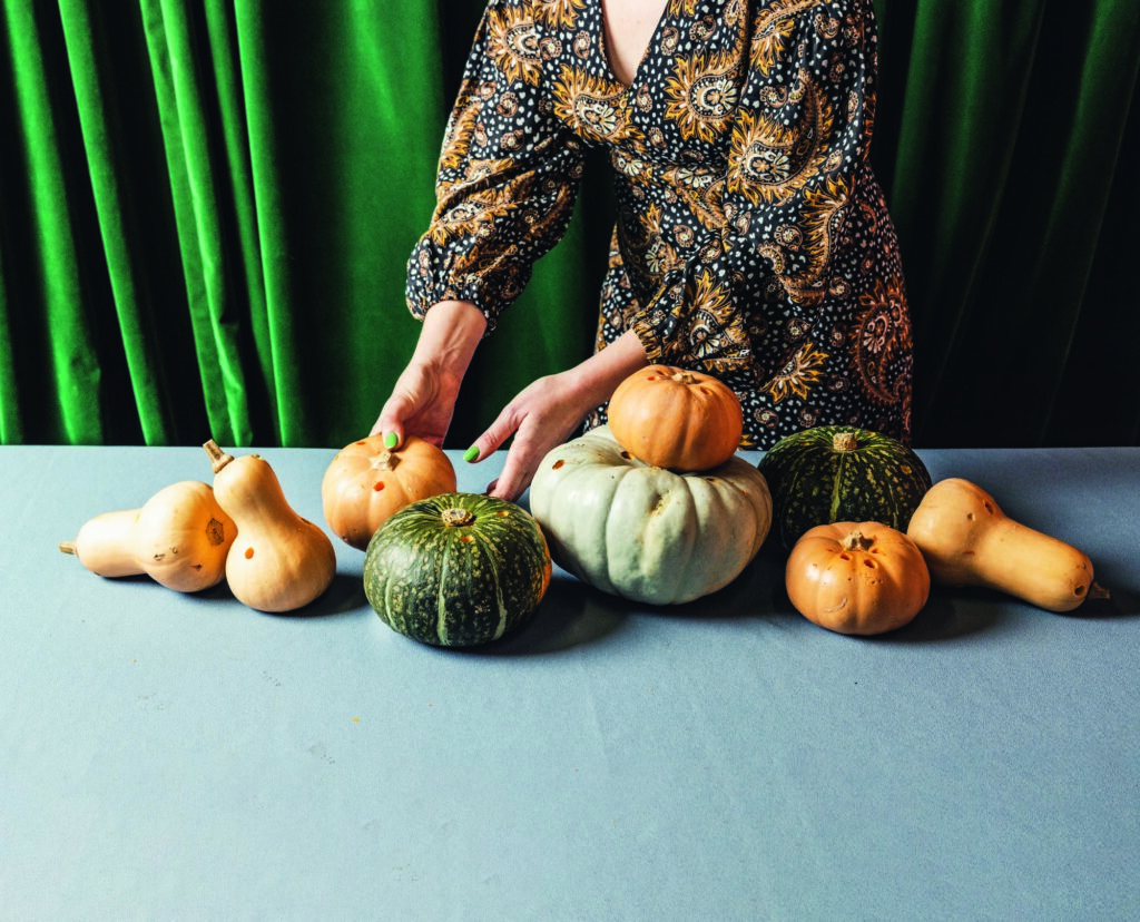 Pumpkins and butternut squash with drilled holes set on a grey table