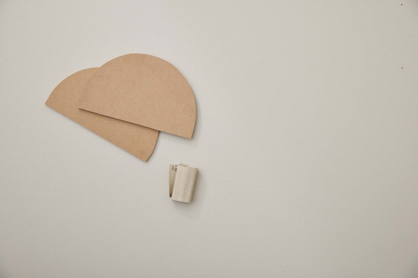 Two oval shapes cut out of an MDF board with a piece of sandpaper next to it