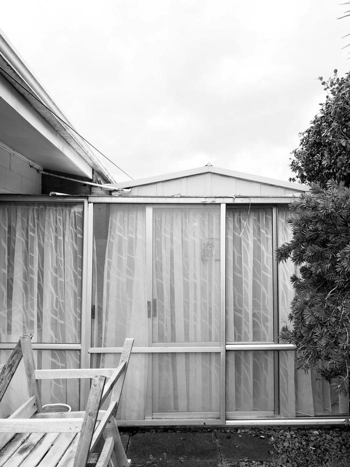 Black and white photo of a shed with fly screens leaning against them