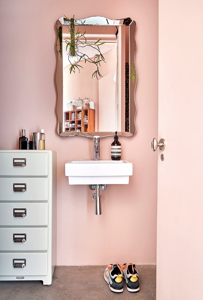 Pink bathroom with curved mirror and metal office styled drawers